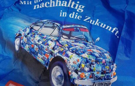 Bildbearbeitung München von sehenundmachen zeigt Werbemittel - Einkaufstüte mit einem Auto von Koppermann und dem Spruch Mit uns nachhaltig in die Zukunft.