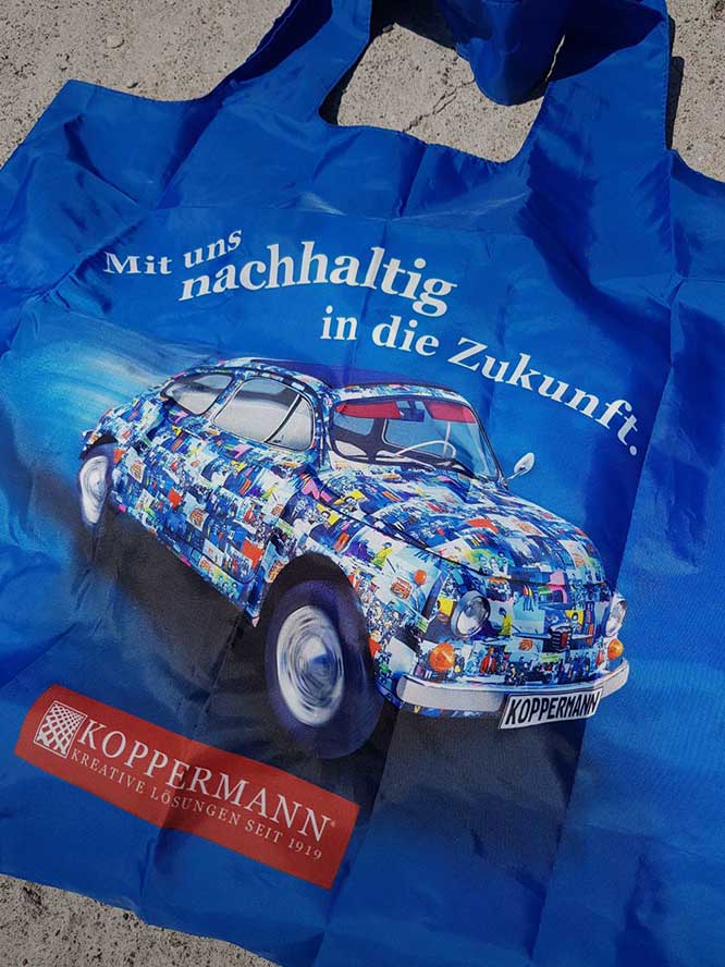 Bildbearbeitung München von sehenundmachen zeigt Werbemittel - Einkaufstüte mit einem Auto von Koppermann und dem Spruch Mit uns nachhaltig in die Zukunft.